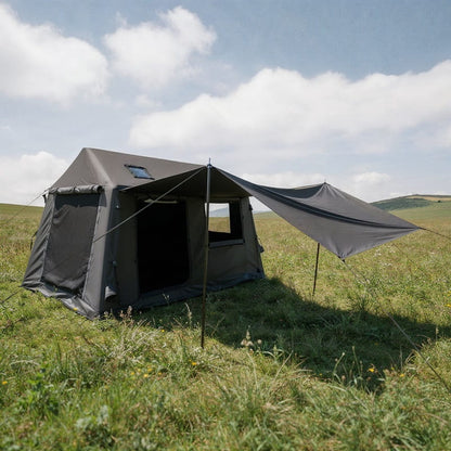 tente gonflable noire avec auvent déployé installée dans une prairie