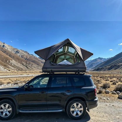 tente de toit gonflable ouverte sur un SUV noir avec vue sur des montagnes