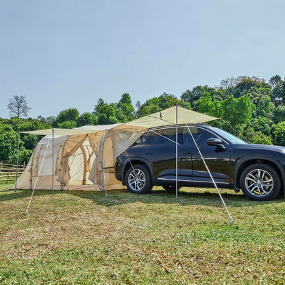 tente gonflable beige fixée à l'arrière d'un SUV noir dans un champ verdoyant